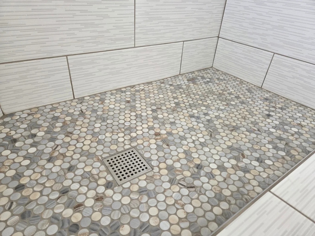 Custom pebble shower tray installation with drain alignment