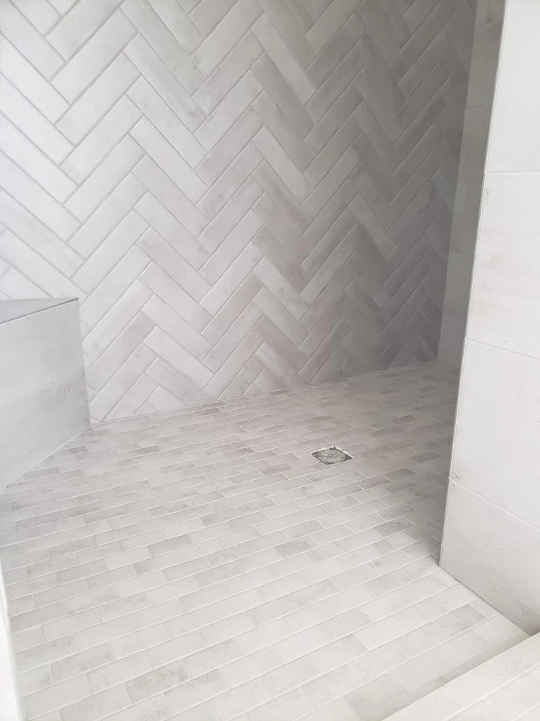 Herringbone wall tile and stacked shower floor tiles